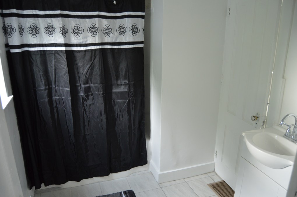 bathroom with black shower curtain and sink. with door