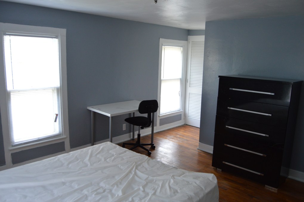bedroom with small desk and black dresser. gray walls and wood floor