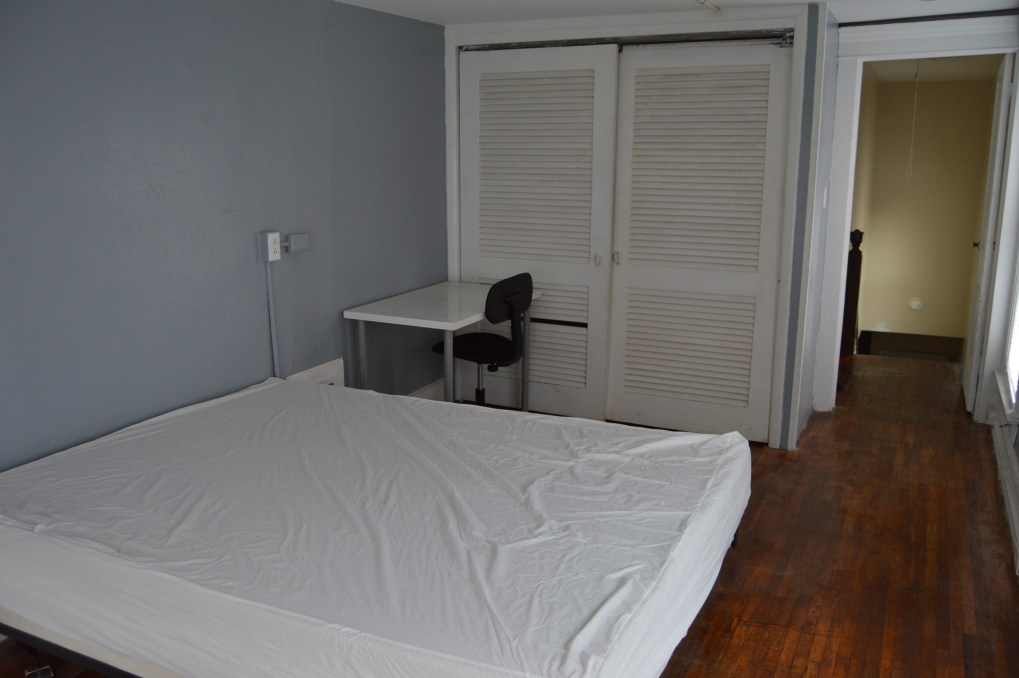 bedroom with small desk and chair with white closet door. gray walls and wood floor
