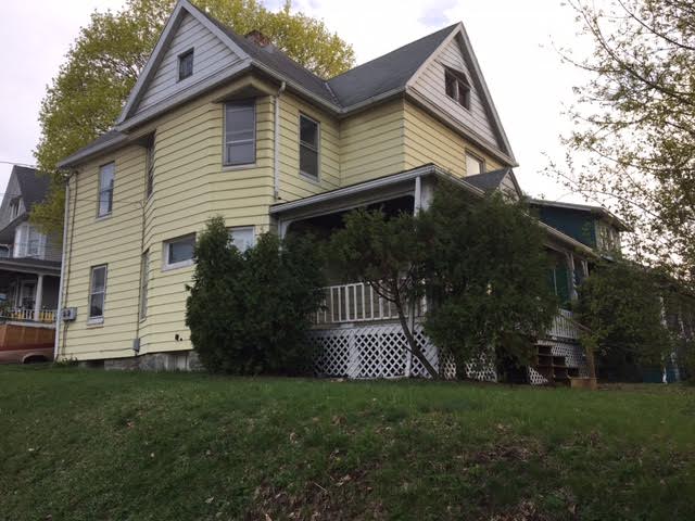 yellow and white house with porch and hedges