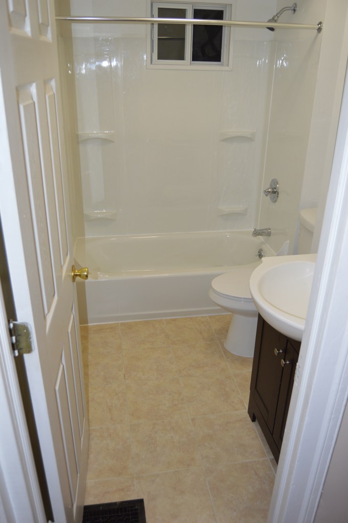 bathroom with white shower, toilet and sink. door