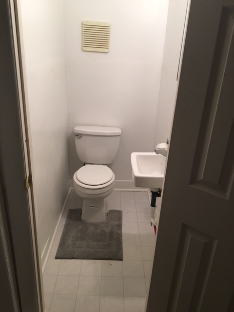 half bathroom with toilet and small sink. gray mat