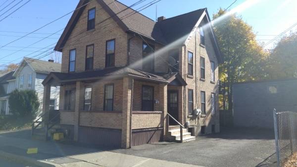 brown brick house with porch and two sets of steps. black top driveway