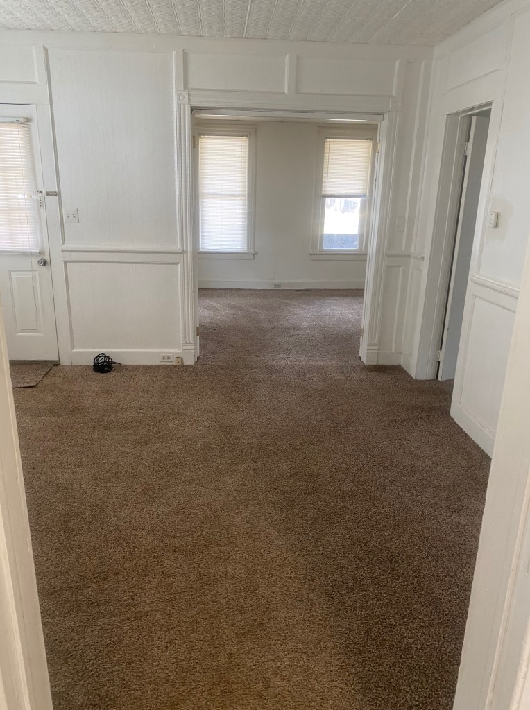livingroom looking into bedroom. carpet through out and doorway.