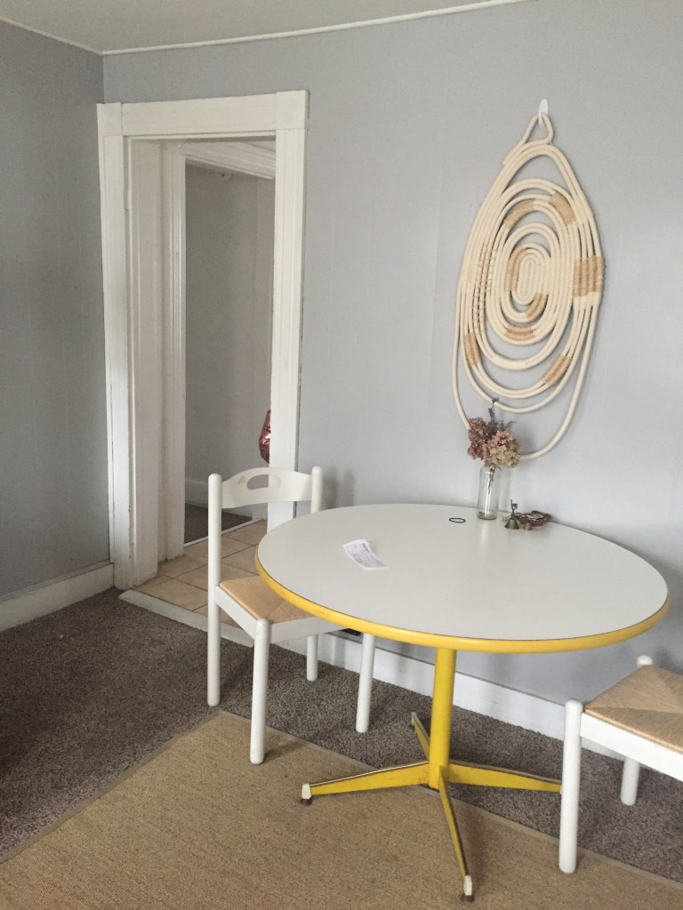 table with two chairs and wall decor, next to entry way
