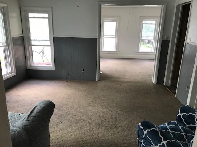 living room with two tone wall with sofa and chair looking into bedroom. multiple windows