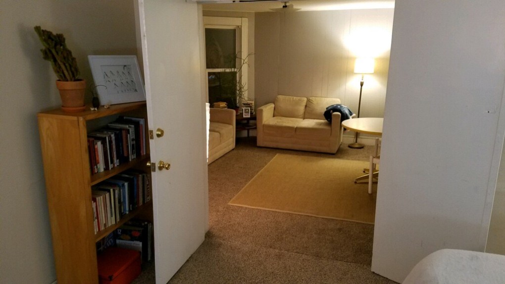living room with two couches with table and light. image taken from bedroom that has book shelf
