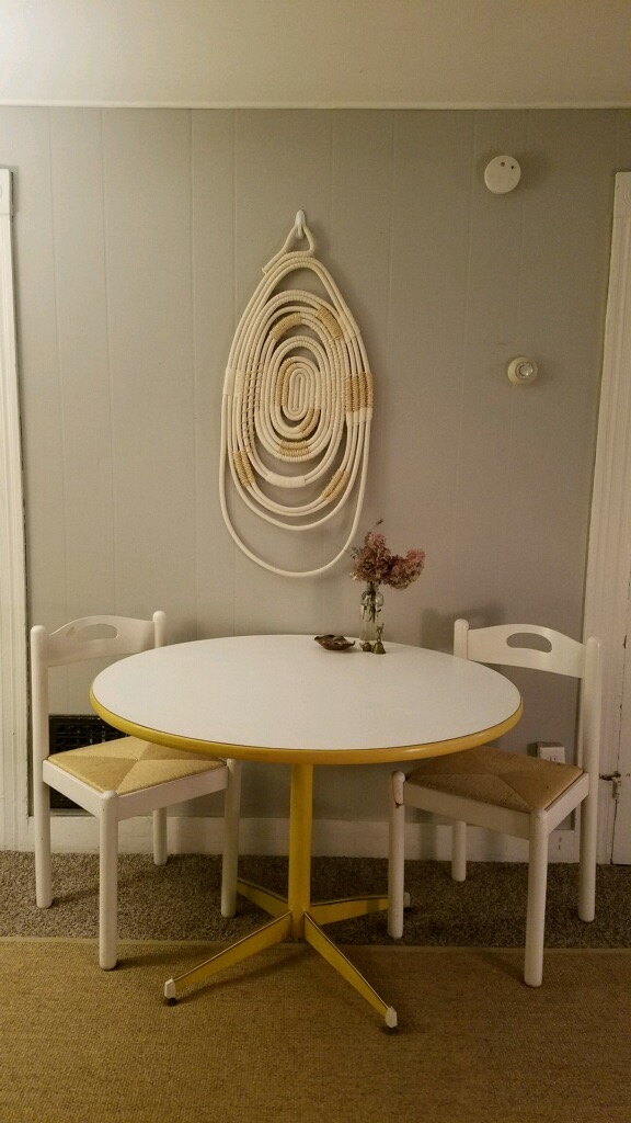 table with two chairs and decorative walling hanging piece