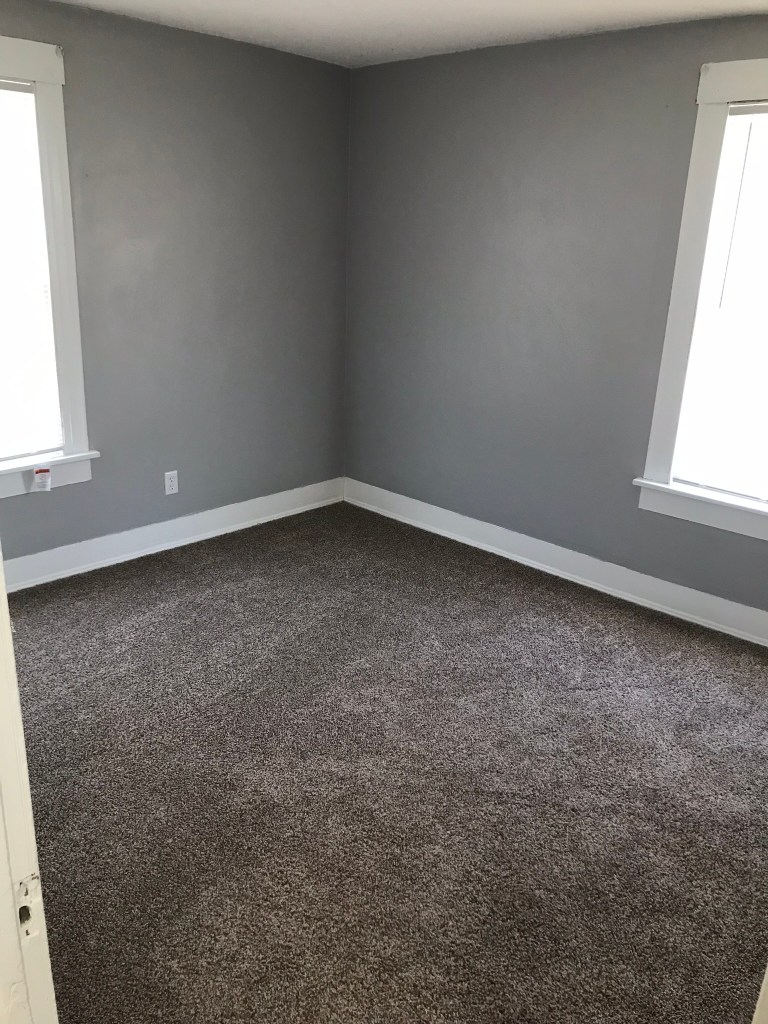 bedroom with gray walls and brown carpet and two windows